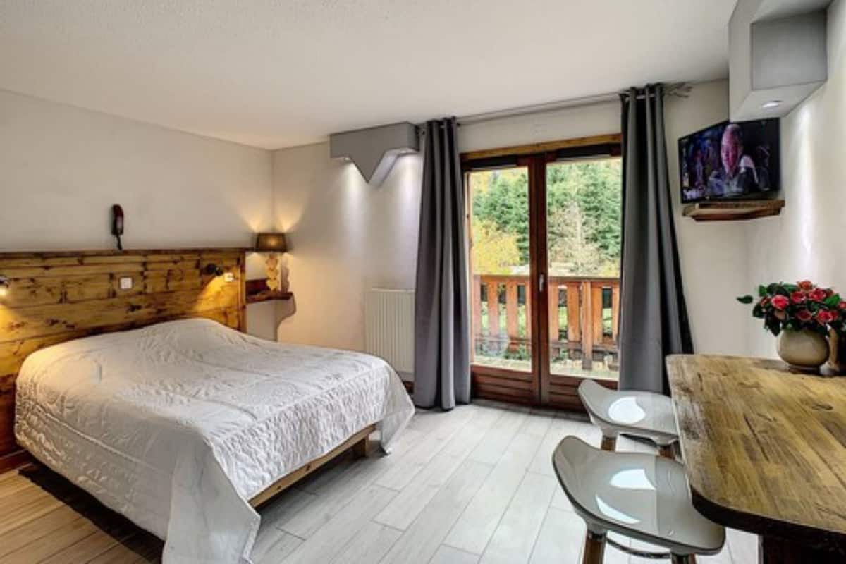 A bedroom with a bed, a desk, and a TV.