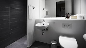 Un baño moderno con lavamanos, espejo y retrete blancos.