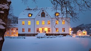 Un edificio grande cubierto de nieve con numerosas ventanas iluminadas y una imponente torre del reloj.