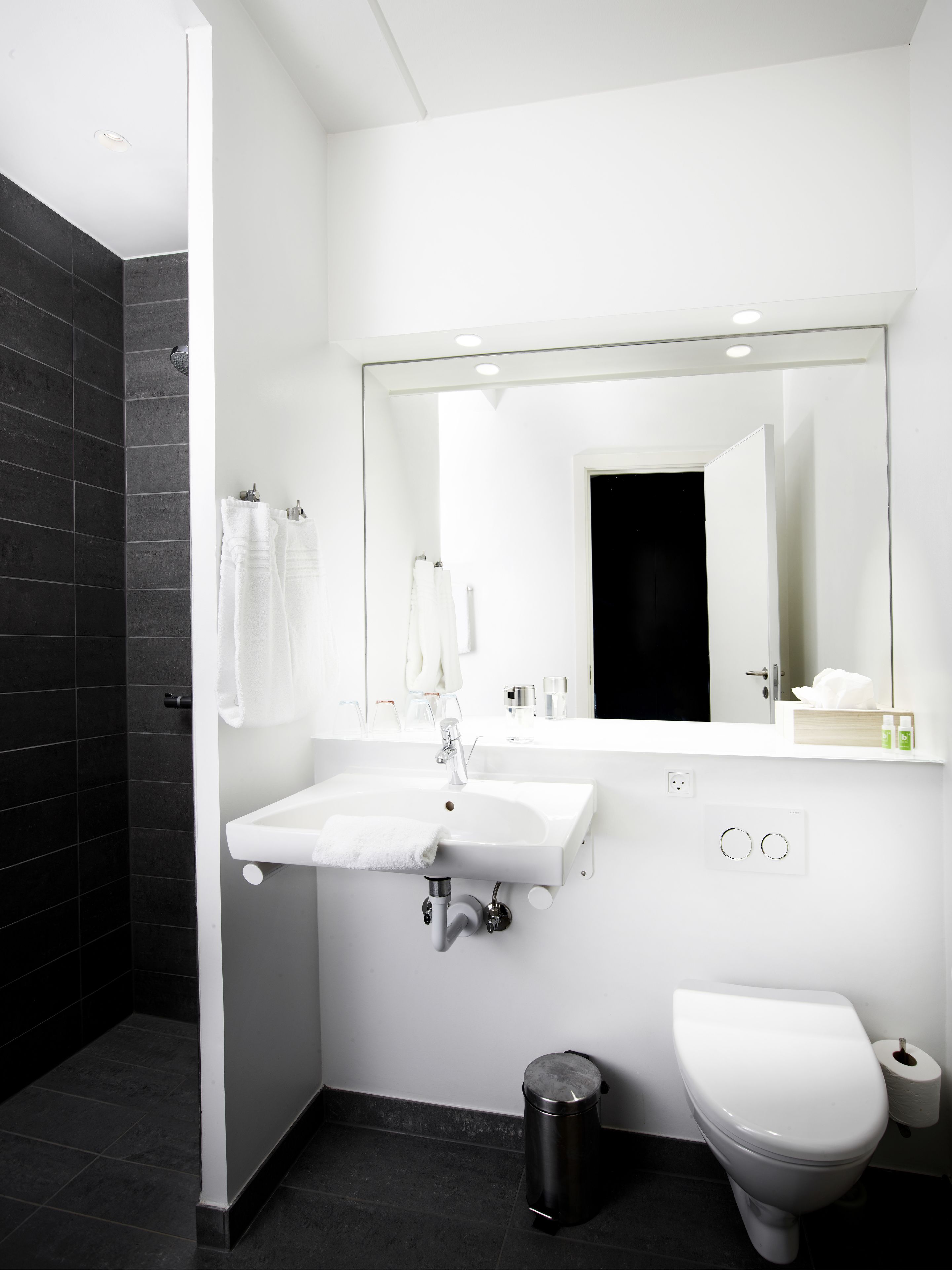 A modern bathroom with a white sink, mirror, and toilet.
