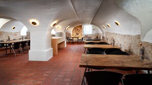 Un comedor con techos altos en arco, suelo de baldosas de terracota y paredes de piedra rústica.