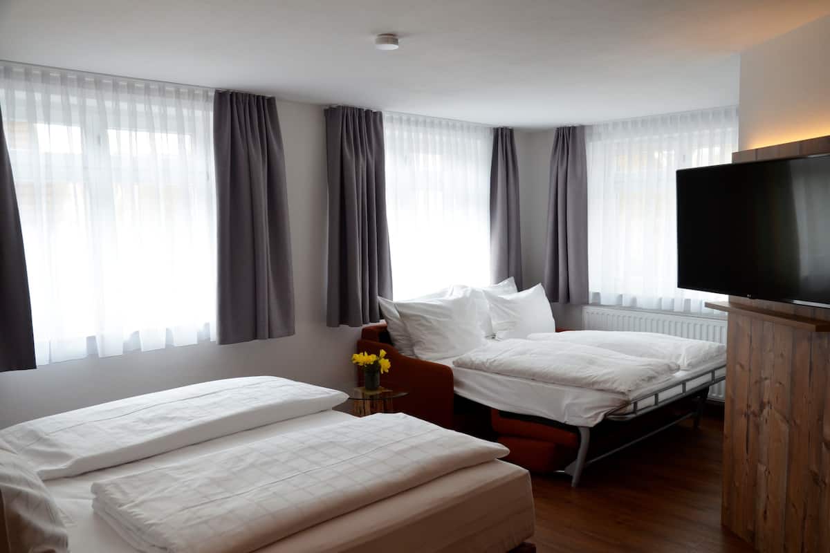 A hotel room with two beds, a TV, and a window with curtains.