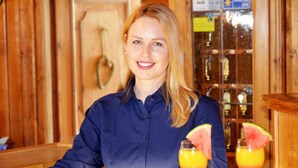 En person sitter i en lokal med träinredning, och i bakgrunden syns en bardisk.