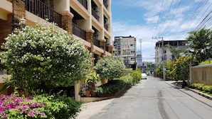 A residential street with multi-story buildings, potted plants, and a clear sky. - Jomtien Beach Residence (Pattaya)