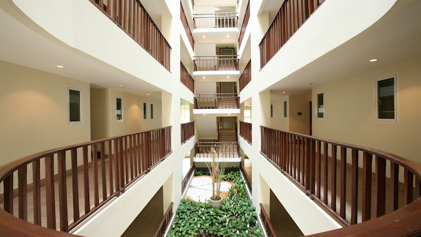 A multi-level atrium with a central garden, wooden railings, and a staircase connecting the floors. - Jomtien Beach Residence (Pattaya)