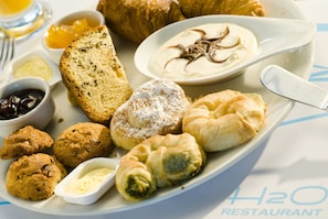 A variety of pastries and desserts on a plate, including croissants, muffins, and a dessert with chocolate sauce.