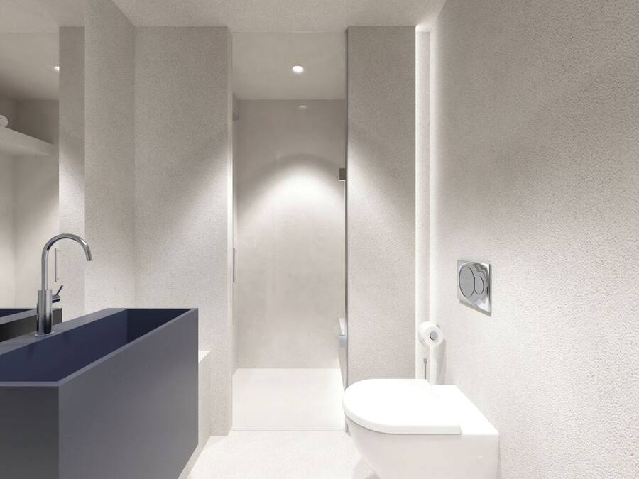 A modern bathroom with a dark blue sink, two faucets, a white toilet, and a shower area.