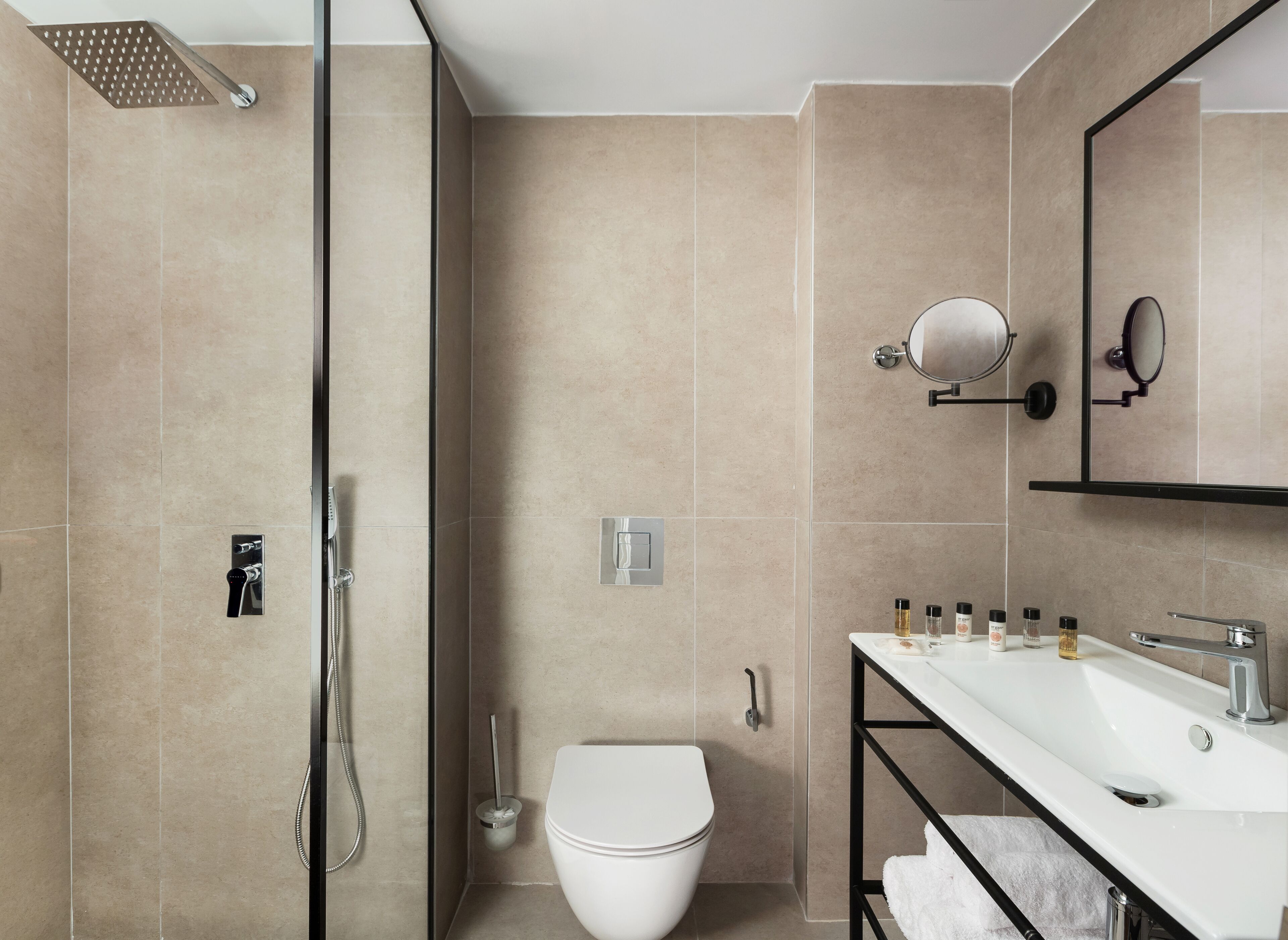 A modern bathroom with a shower, toilet, sink, and a mirror.