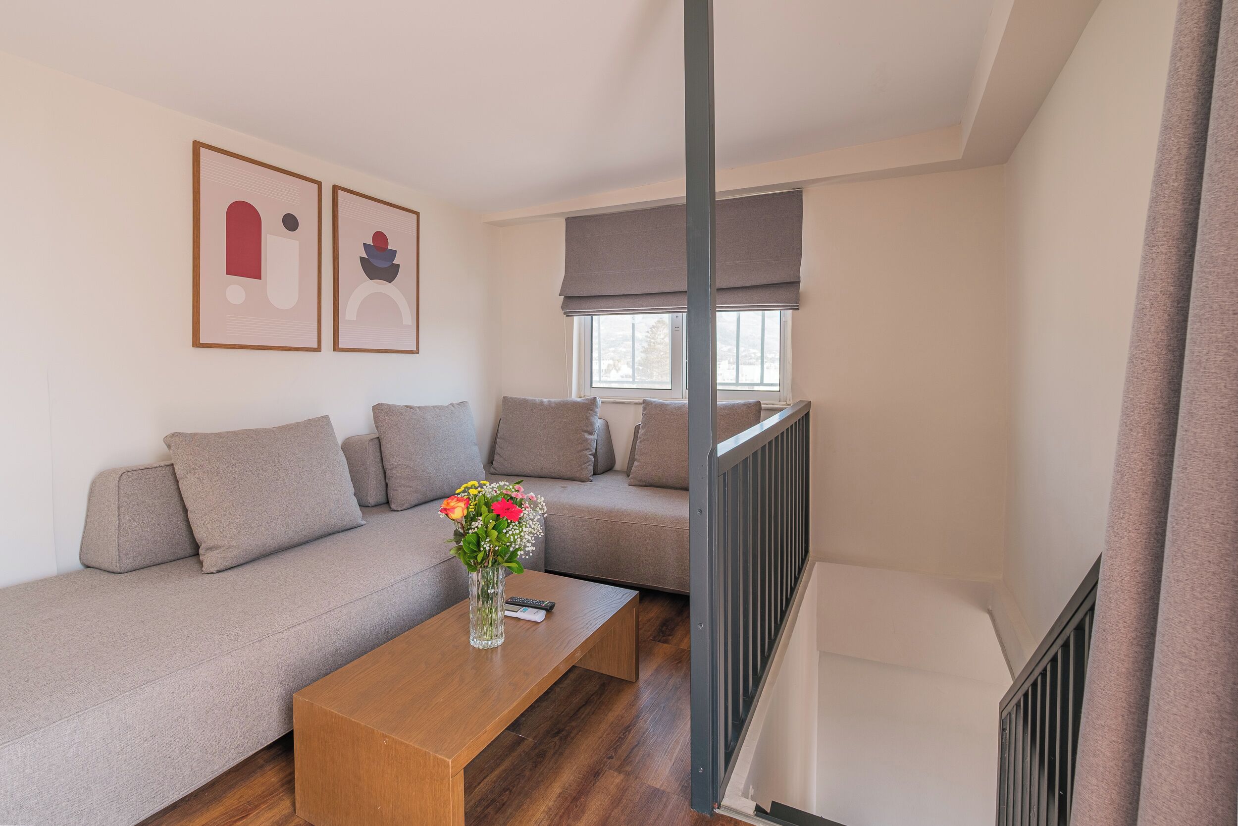 Una sala de estar moderna con un sofá, una mesa de centro y un jarrón con flores.