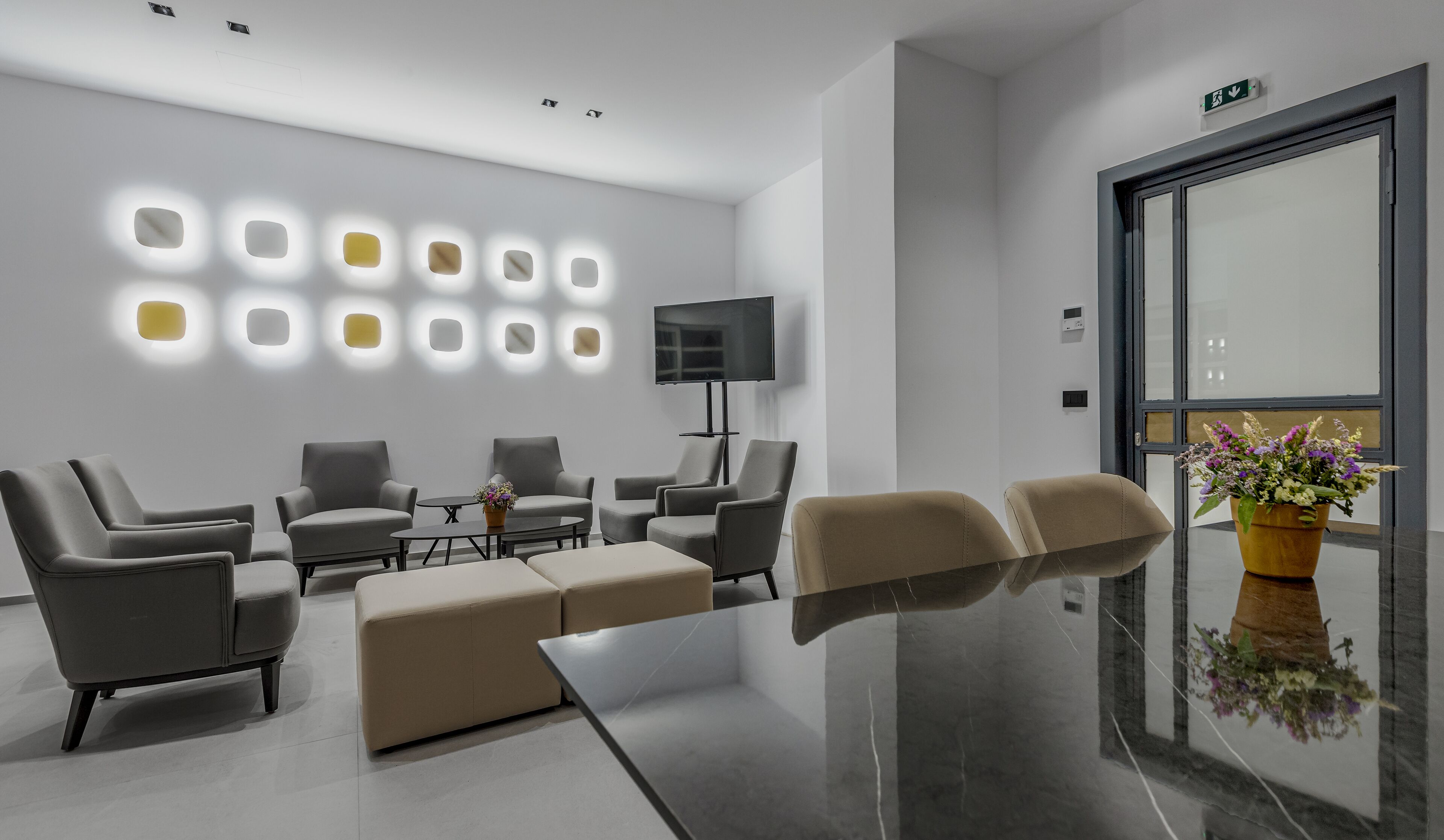 Un espace d’attente moderne, doté de canapés, d’une table basse et d’un téléviseur.