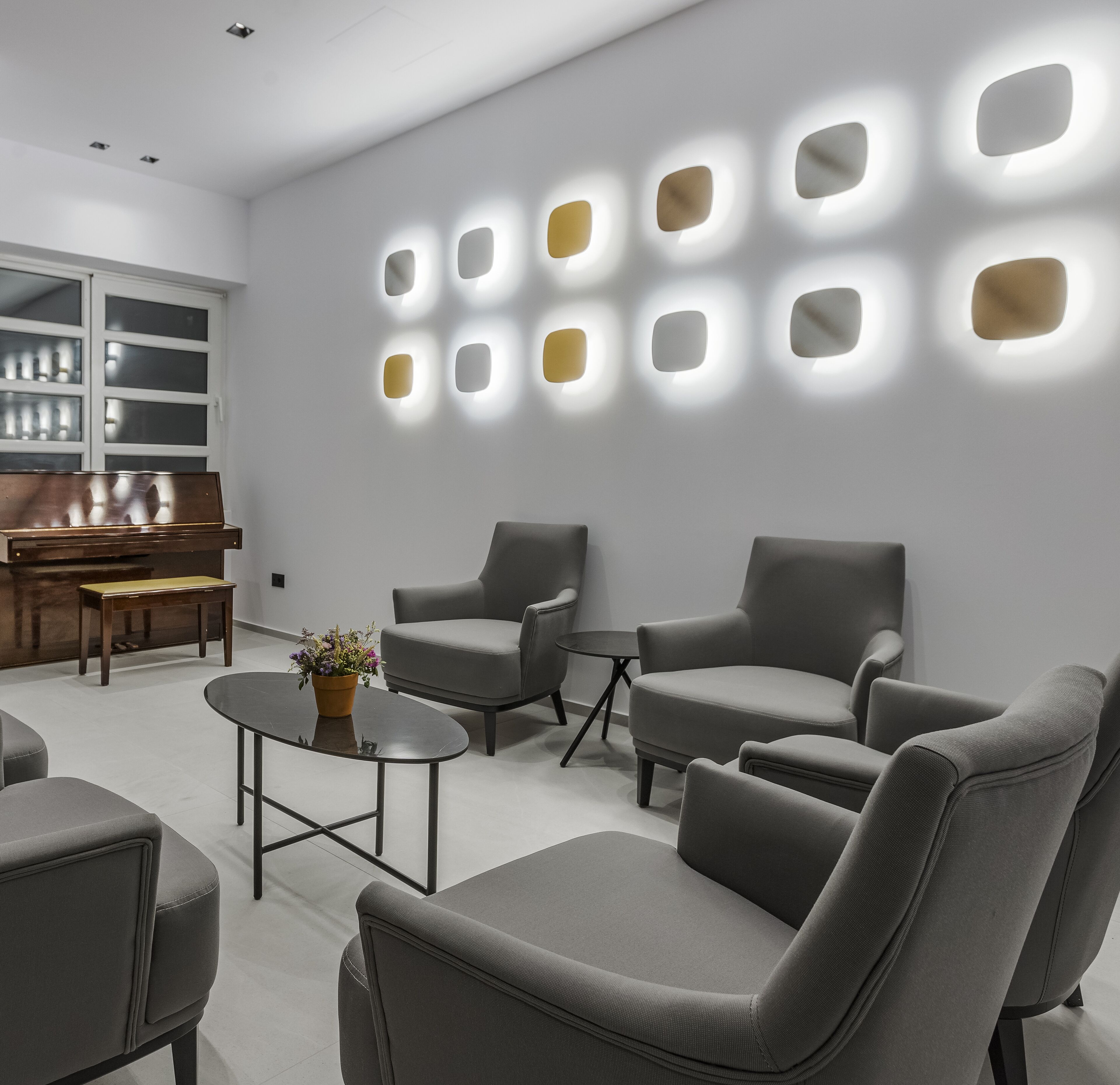 A modern living room with grey sofas, a coffee table, and a piano.