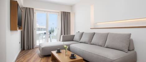 A modern living room with a grey sofa, a wooden coffee table, and a balcony with white chairs.