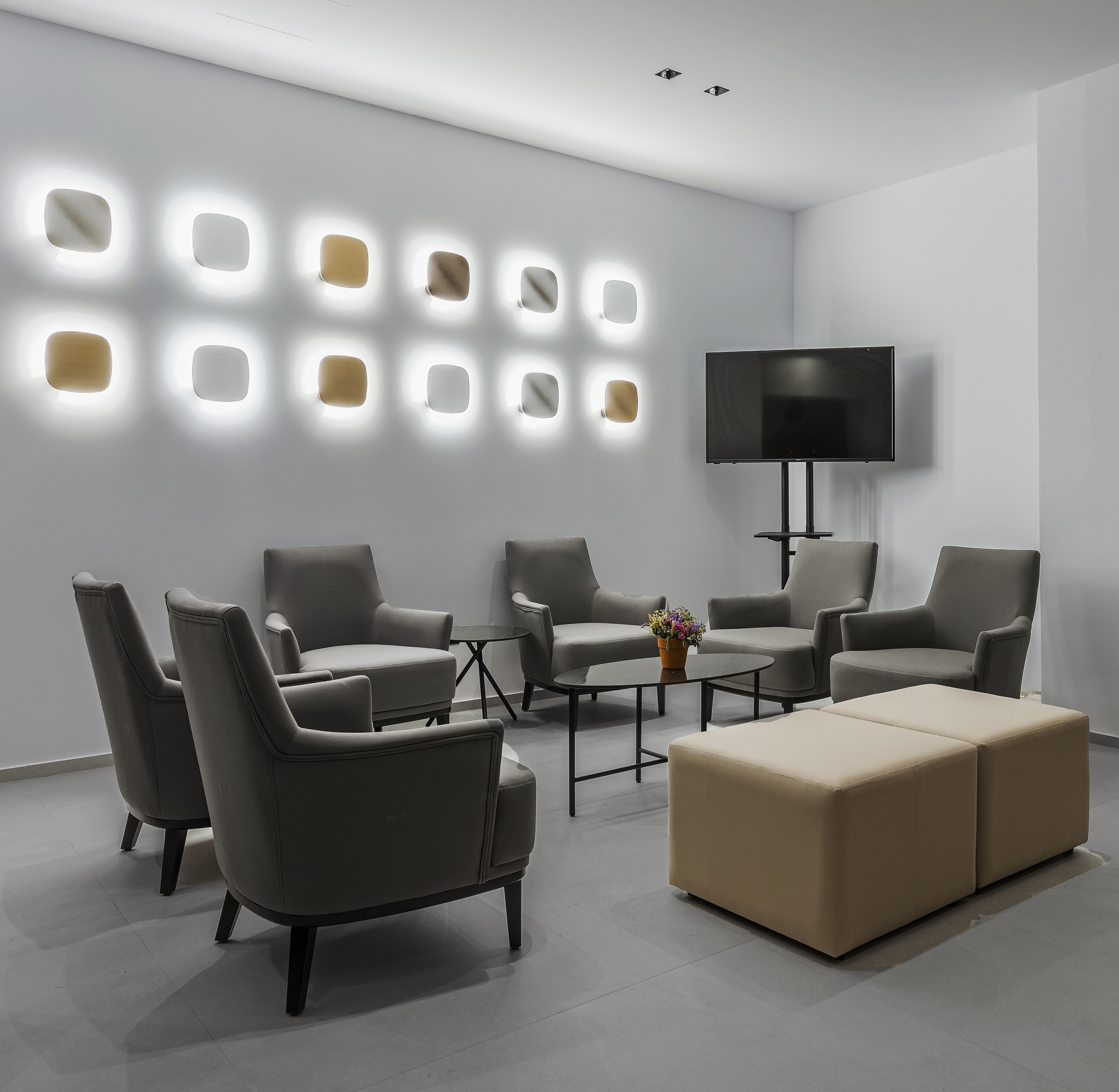 A modern living room with a sofa set, a coffee table, and a flat-screen TV mounted on the wall.