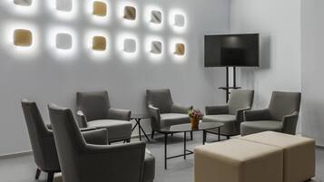 A modern living room with a sofa set, a coffee table, and a flat-screen TV mounted on the wall.