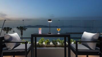 A balcony with two chairs, a table, and two drinks.