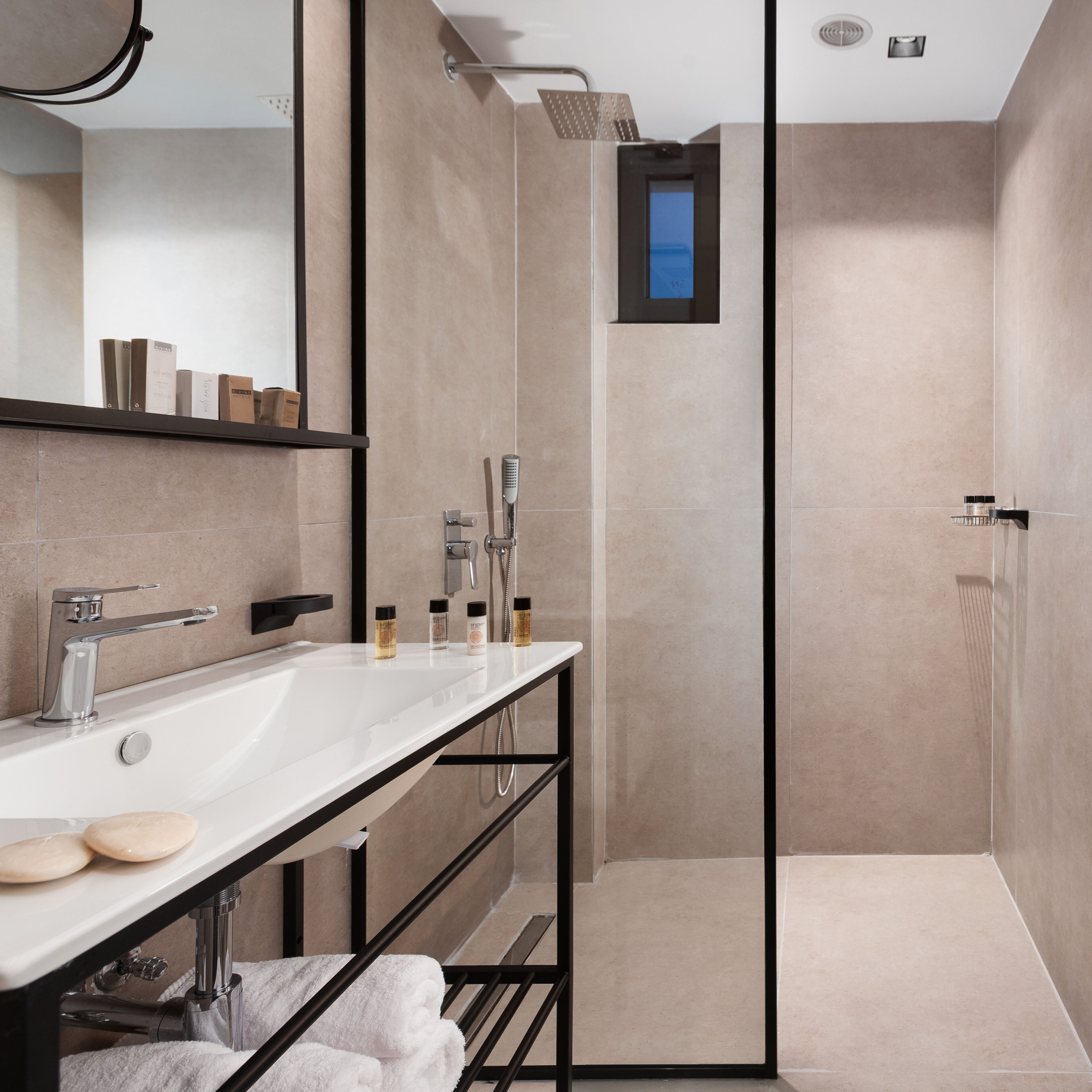 A modern bathroom with a white sink, black towel rack, and a glass shower enclosure.