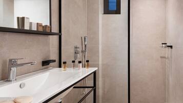 A modern bathroom with a white sink, black towel rack, and a glass shower enclosure.