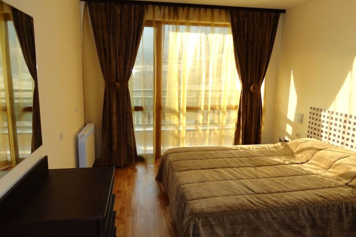 Habitación de hotel con cama, escritorio y vistas al exterior.