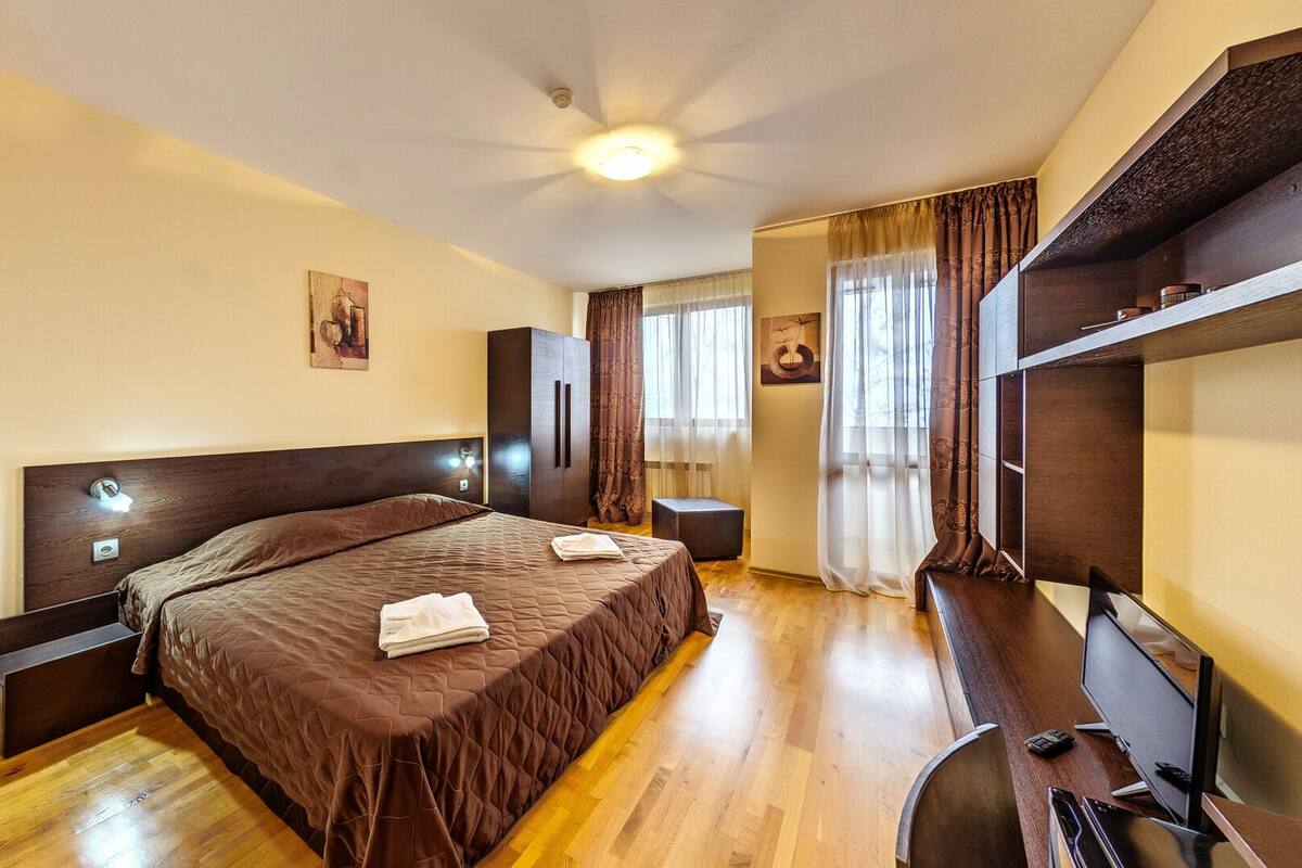 Una habitación de hotel con una cama grande, un escritorio con silla, un armario y una televisión.