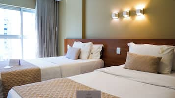 Une chambre d’hôtel avec deux lits, une fenêtre avec des rideaux et un luminaire fixé au mur.