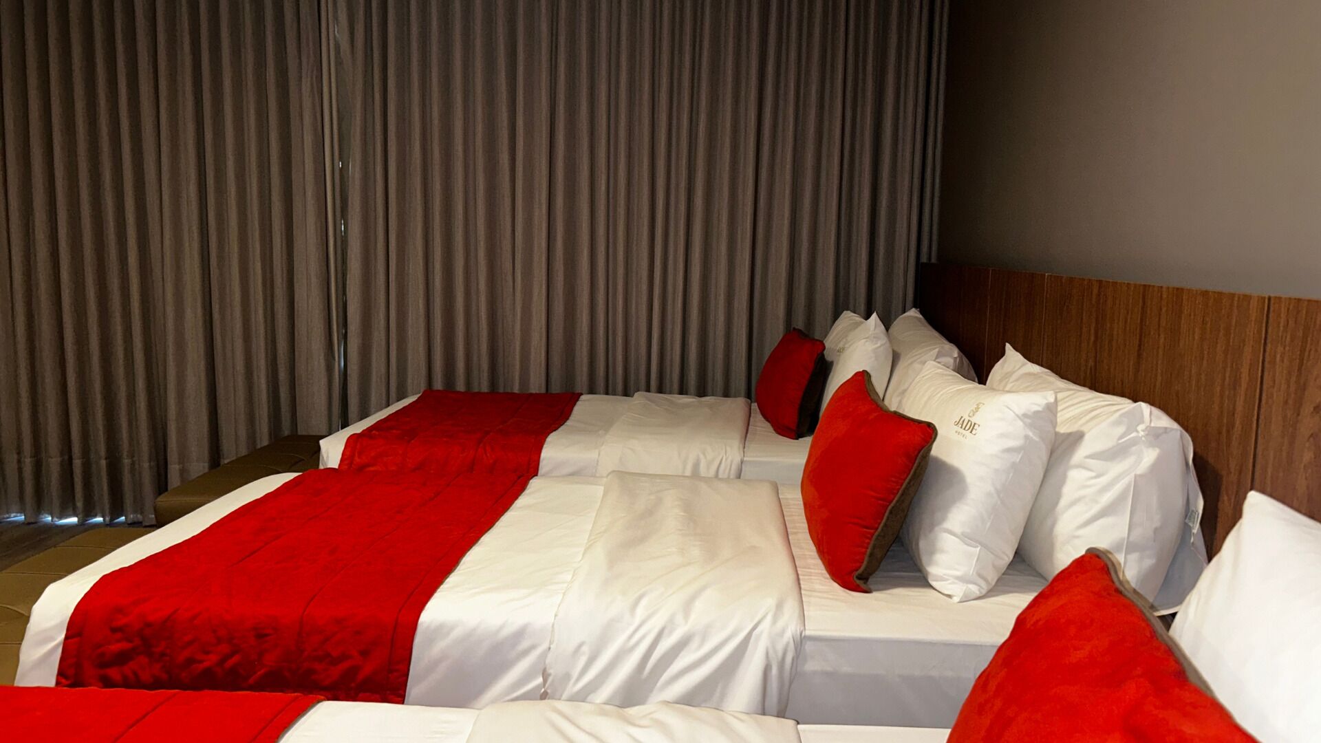 A hotel room with two beds, each with white bedding and red accents, and a wooden headboard.