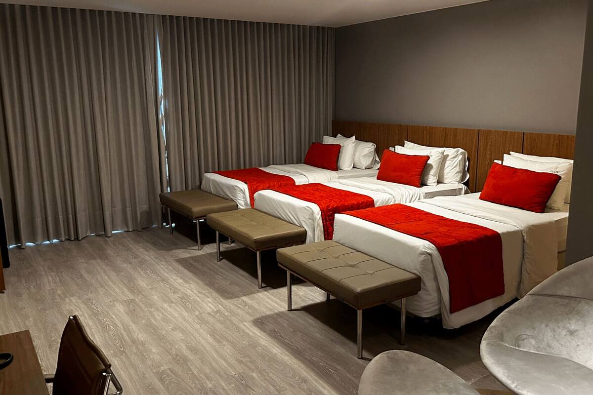 A hotel room with two beds, a desk, and a chair.