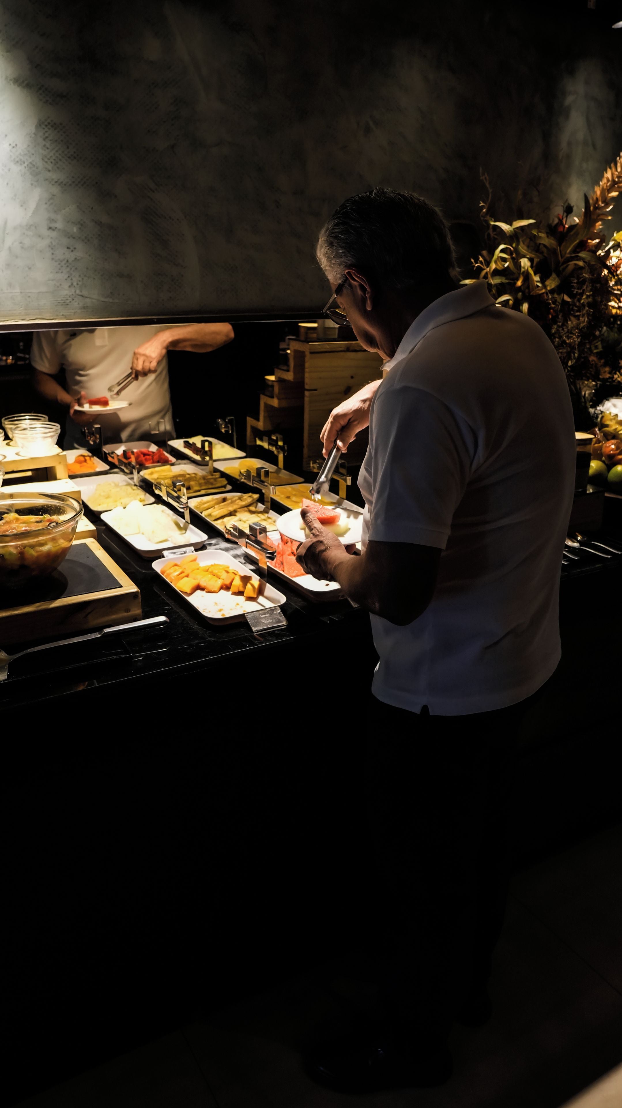 A buffet setup with various food items and a person serving.