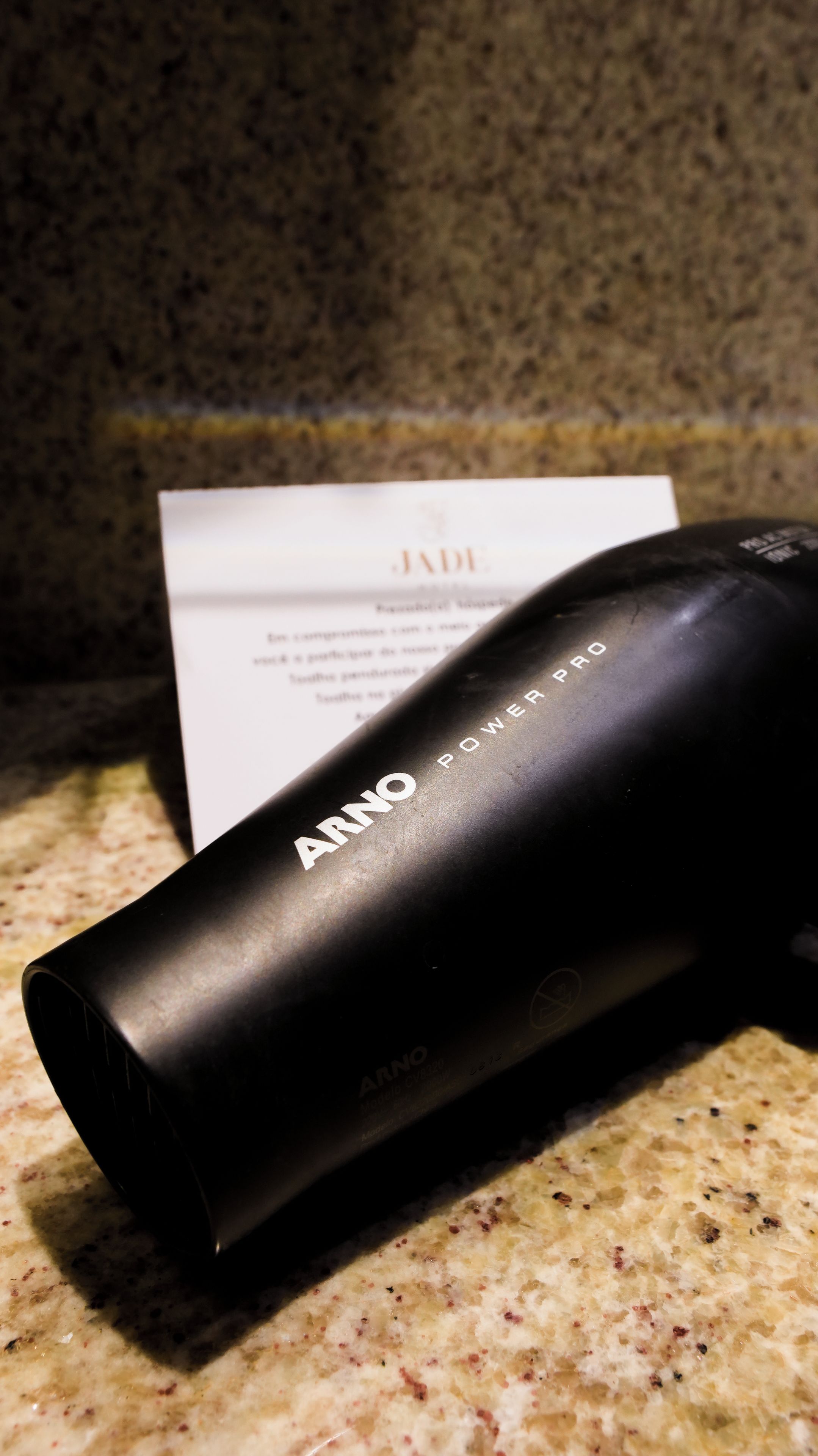 Un secador negro con el nombre de la marca 'ARNO' sobre una encimera de granito.