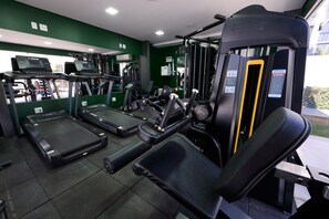 Una palestra con tapis roulant, macchinari per pesi e panche.