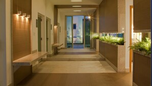 Un couloir moderne avec un plancher en bois, un éclairage encastré et une porte en verre donnant sur un balcon agrémenté de plantes.
