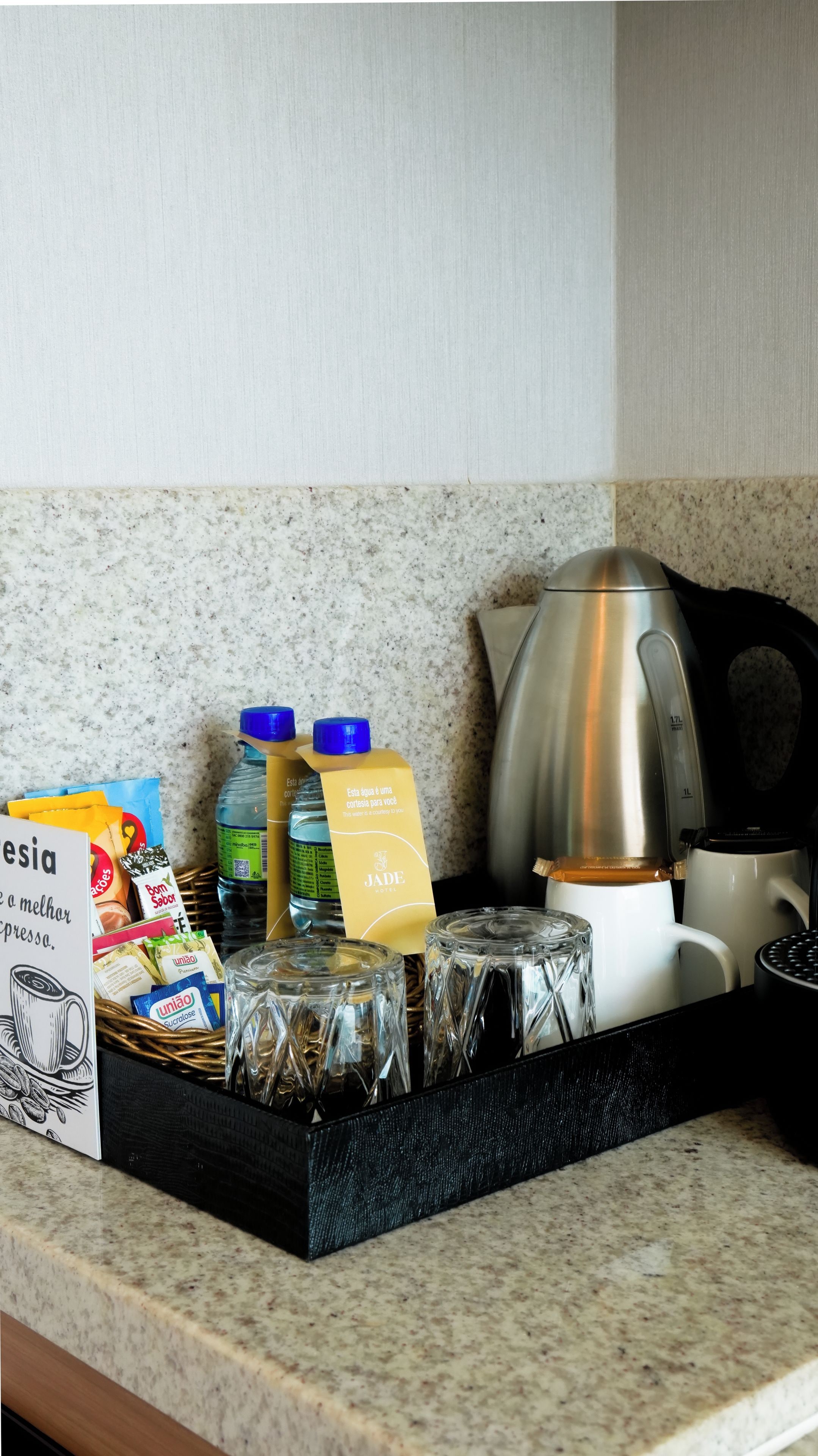 Eine Küchenarbeitsplatte mit Kaffeemaschine, Wasserkocher, einer Wasserflasche, einer Saftpackung und einer Kapselbox.