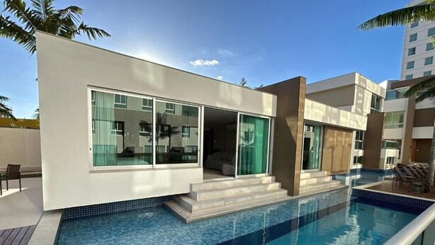 Un bâtiment moderne doté d’une piscine, de grandes fenêtres en verre et d’un toit plat.