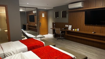 Una habitación de hotel con dos camas, un escritorio, una silla, un televisor y un aire acondicionado.