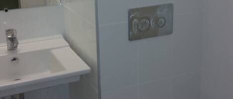 A bathroom with a white sink, mirror, and toilet.