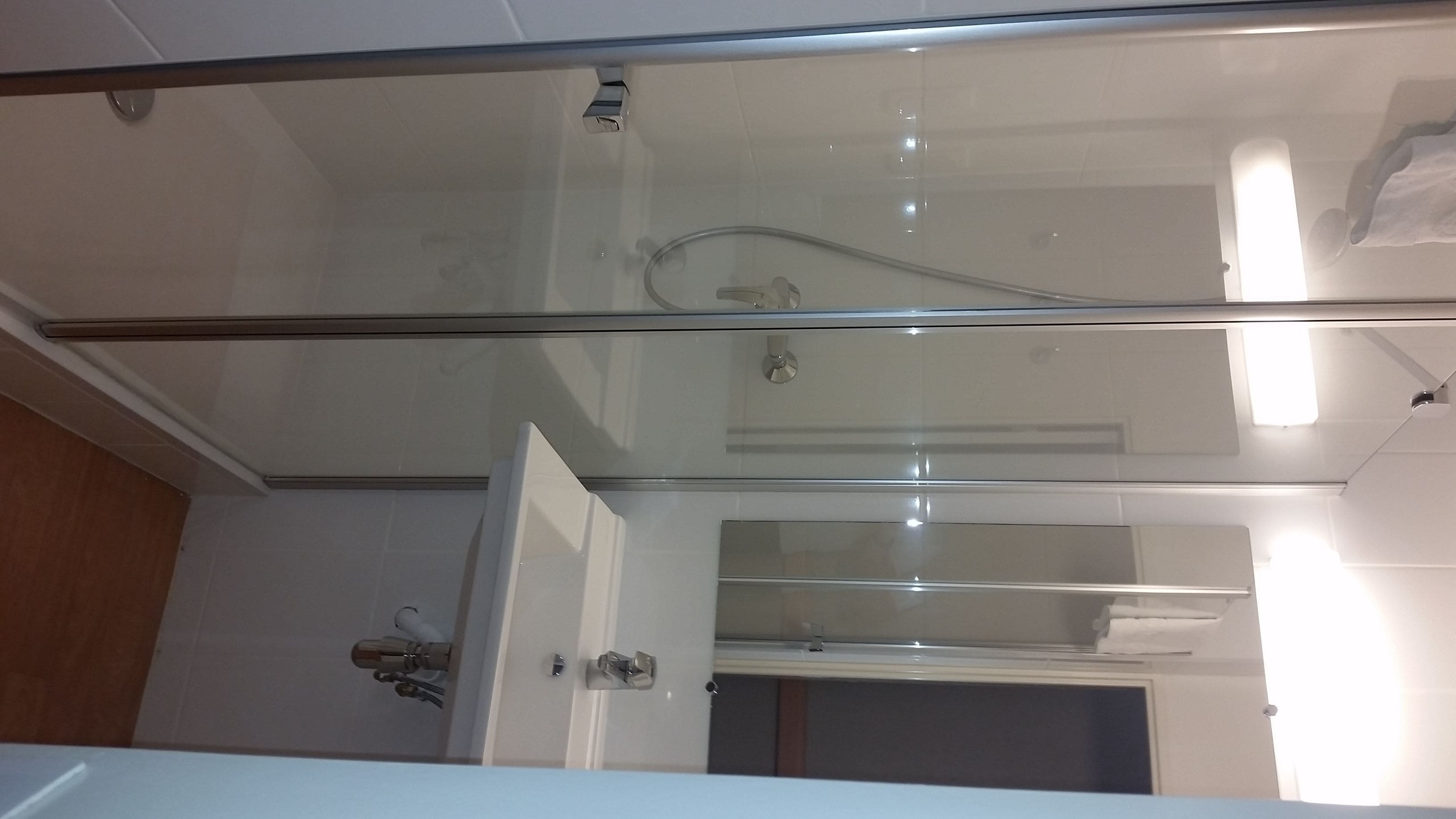 Une salle de bain moderne avec une douche à parois de verre, un lavabo blanc et un miroir.