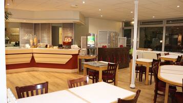 Een restaurant met een toonbank, tafels en stoelen.