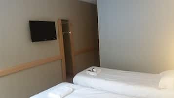 Habitación de hotel con cama, televisor montado en la pared y detalles en paneles de madera.