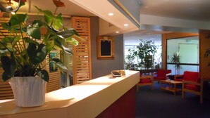 A reception area with a counter, potted plants, and seating. - Hôtel Inn Design Moutiers (Moutiers)