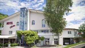 A hotel with a prominent 'HOTEL' sign, a glass elevator, and a covered outdoor seating area. - Hotel Restaurant Hohberg (Schaffhausen)