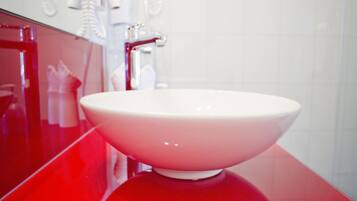 Un baño moderno con encimera roja, un lavabo blanco y un espejo con iluminación.