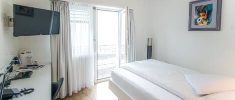 A hotel room with a bed, desk with a computer, and a TV.