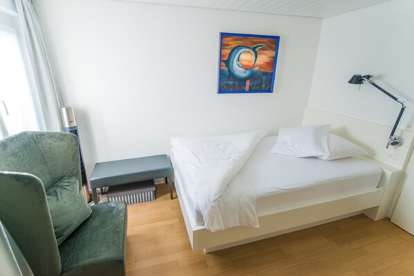 A hotel room with a bed, a bench, a desk, and a painting on the wall. - Hotel Restaurant Hohberg (Schaffhausen)