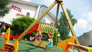 A playground with swings and a slide, a wooden play structure, and a building with a sign that reads "HOTEL." - Hotel Restaurant Hohberg (Schaffhausen)