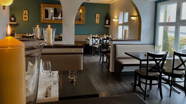 A restaurant interior with tables, chairs, candle-lit centerpieces, and large windows. - Hotel Restaurant Hohberg (Schaffhausen)