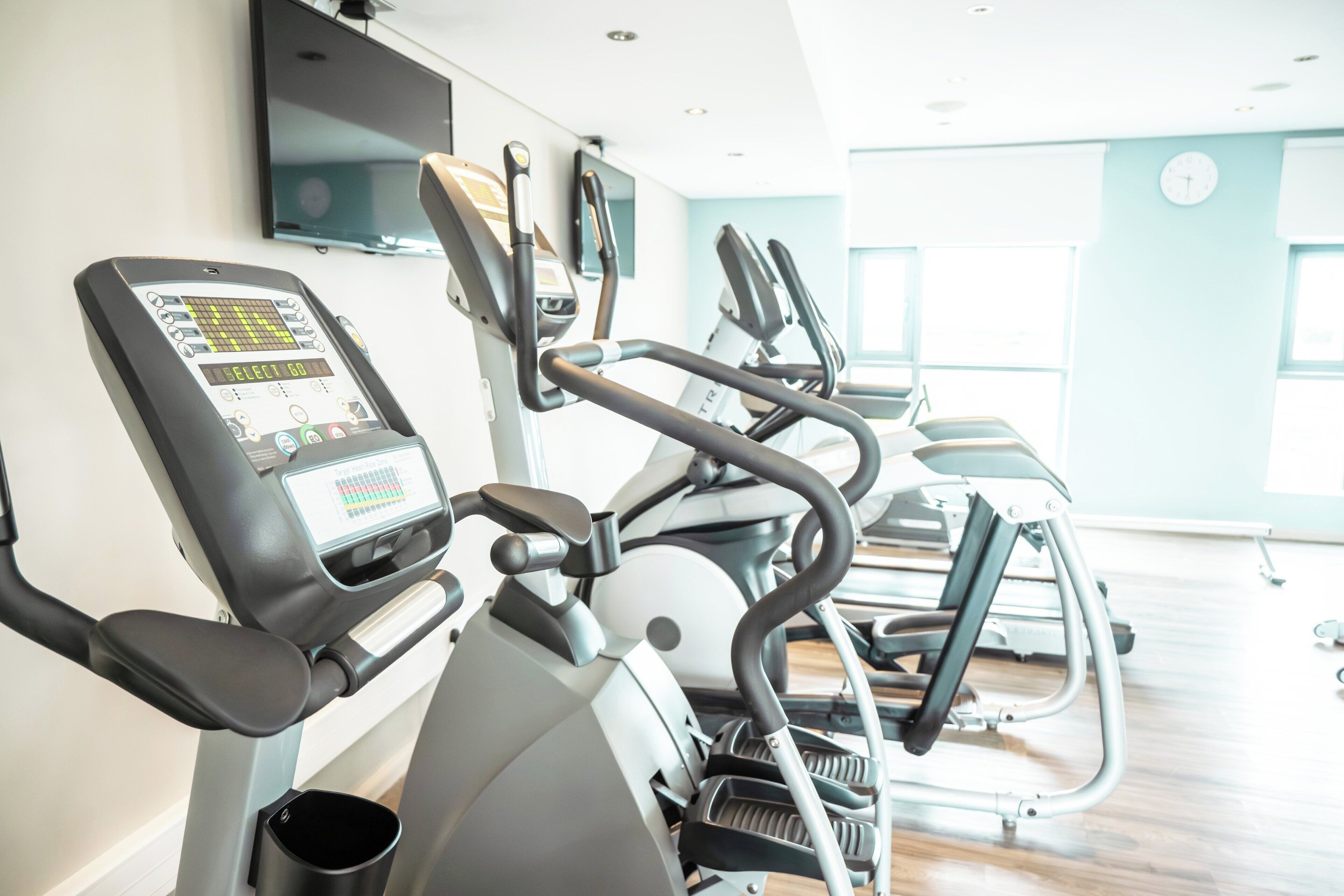 Une salle de sport équipée de tapis de course, d’un vélo d’appartement et d’un appareil d’aviron.