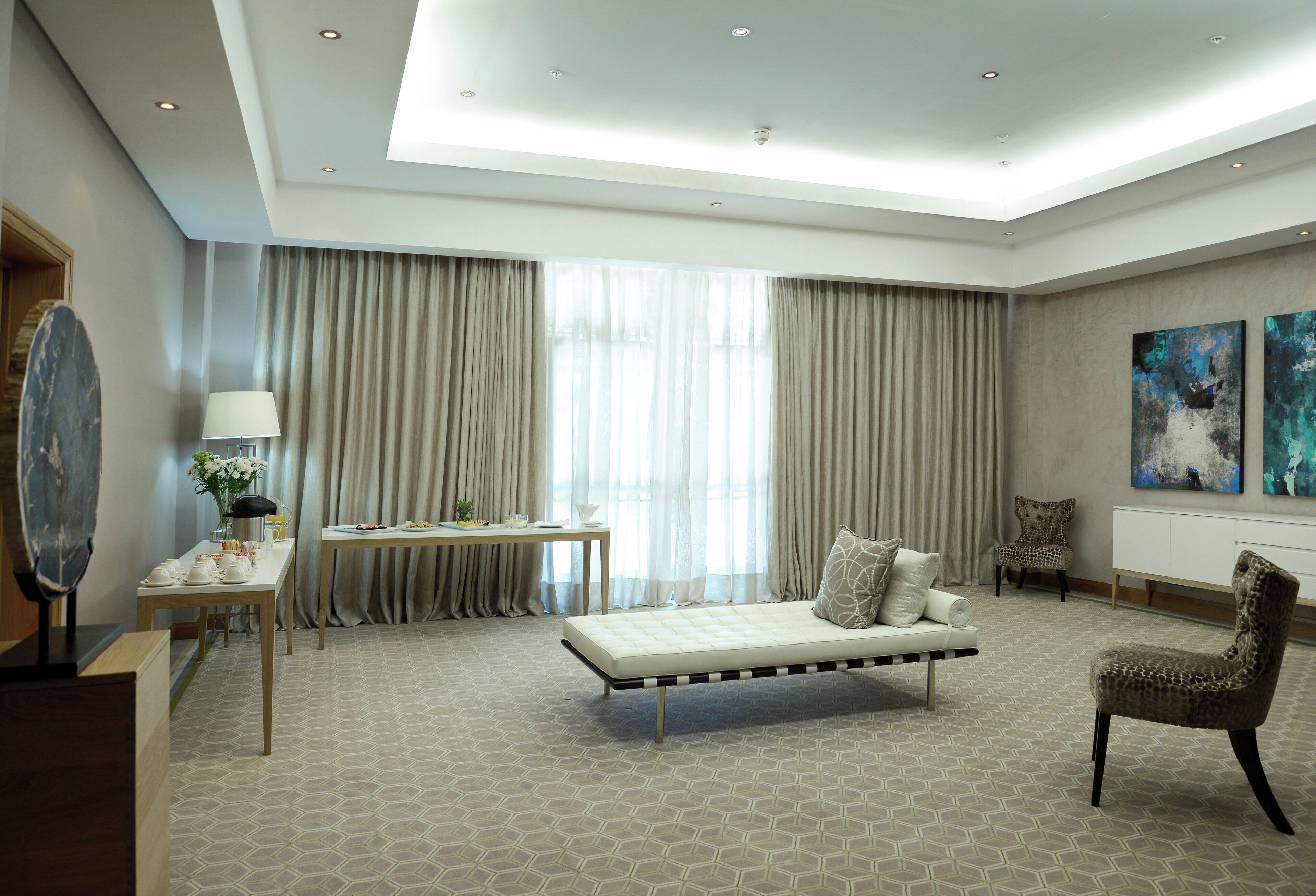 Habitación de hotel con cama, escritorio, silla y obras de arte en las paredes.
