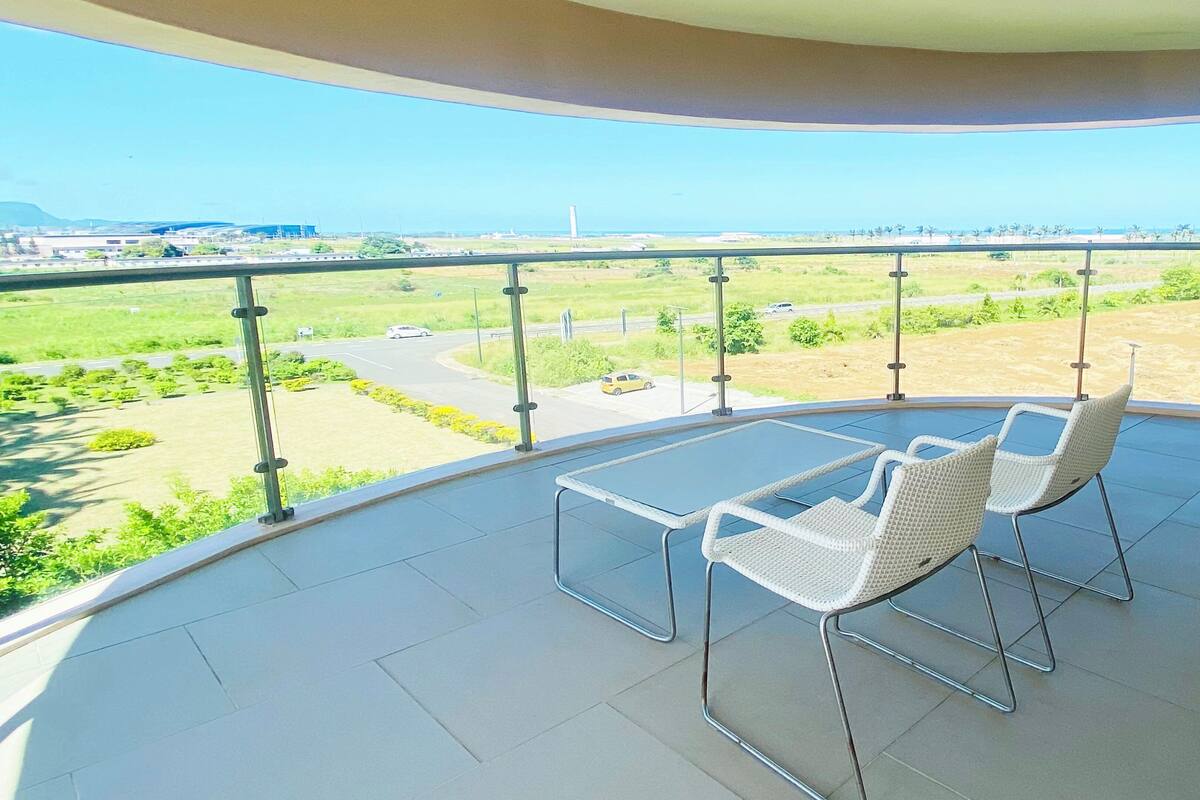 Un balcon doté d’une balustrade en verre, d’une table et de deux chaises.