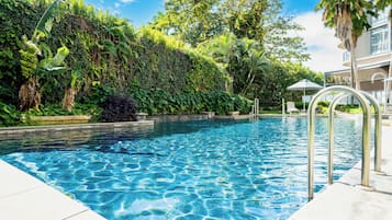 Una piscina al aire libre, sombrillas, sillones reclinables de piscina