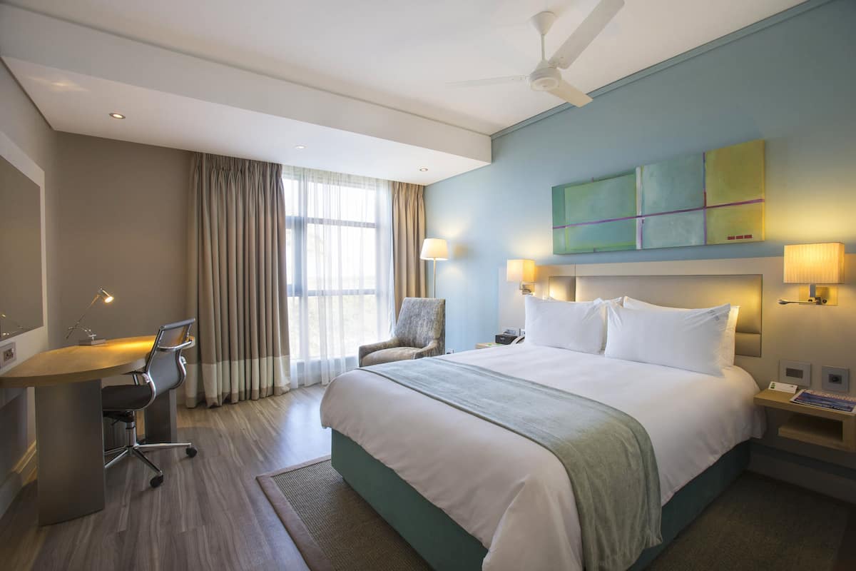 Une chambre d’hôtel équipée d’un lit, d’un bureau, d’une chaise et d’un ventilateur de plafond.