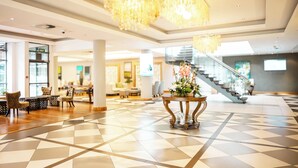 A spacious lobby with a checkered floor, a staircase, and a table with a floral arrangement. - Holiday Inn Mauritius Mon Tresor by IHG (Plaine Magnien)